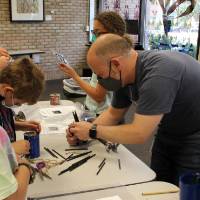 Students work on their bee house projects with a teacher